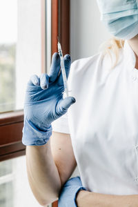 Midsection of doctor holding syringe