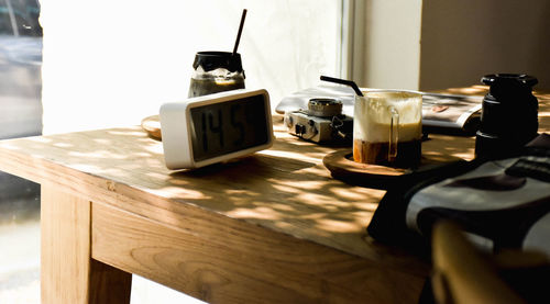 Close-up of digital clock and coffee cup on table