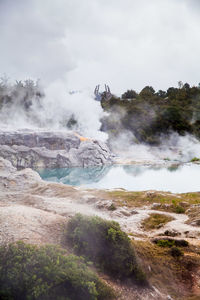 Scenic view of hot spring against cloudy sky