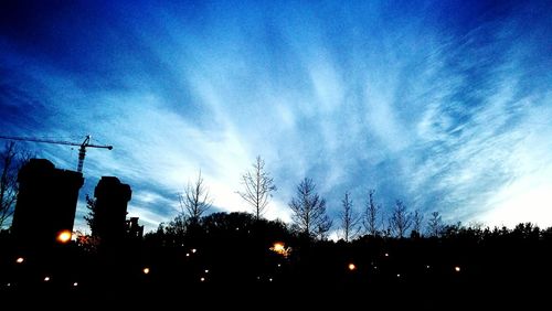 Low angle view of silhouette trees against blue sky at sunset