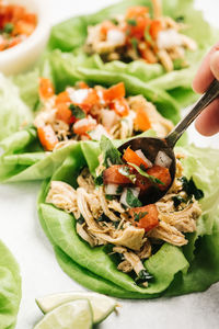 Adding pico de gallo to chicken lettuce tacos with a spoon