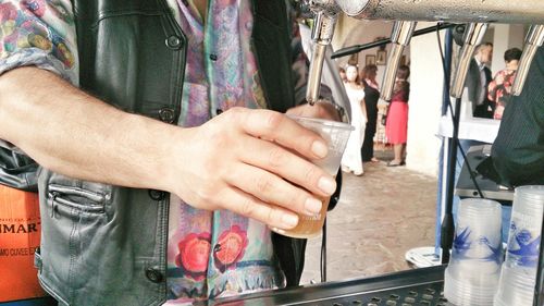 Man holding disposable glass under soda machine