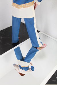 Fashion portrait of ginger woman in fashionable stylish summer suit standing on mirror, studio