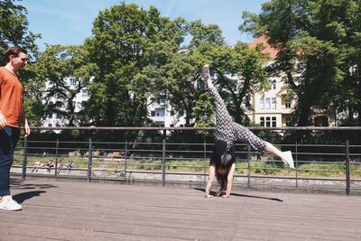 Young man obesrving young woman doing cartwheel