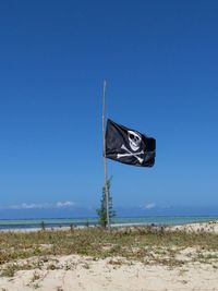 Pirate flag in blue sea against clear sky