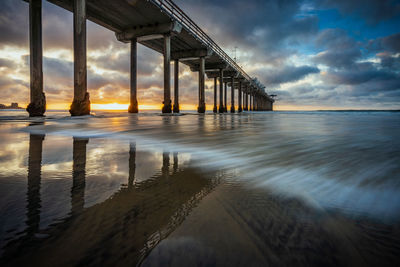 Bridge over sea against sky during sunset