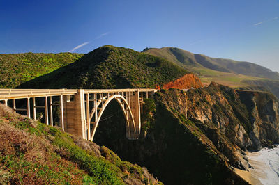 Low angle view of bridge over mountain against clear sky