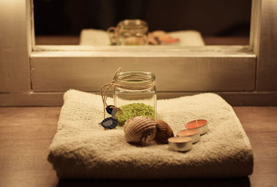 Close-up of tea lights and seashells on towel