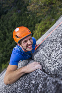 Climber looking up and laughing while rock climbing with helmet chief