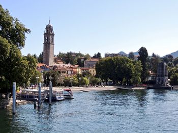 Sailboats in river by buildings against clear sky