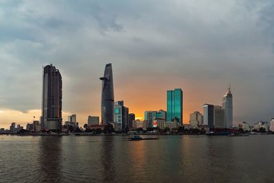 City at waterfront against cloudy sky