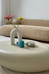 Gerbera flowers and a cup of coffee on a table in a beige bedroom