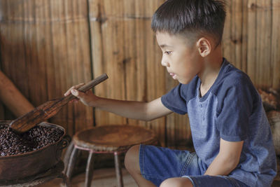 Boy looking away while sitting on wood