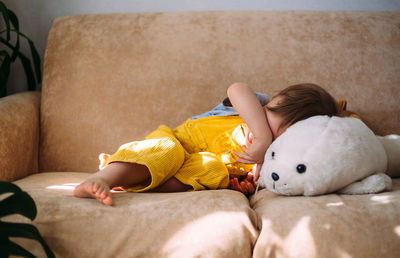 Low section of woman lying on sofa at home