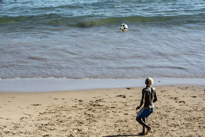 Young model playing sand football on the beach under strong summer sun. salvador bahia brazil.