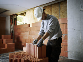 Bricklayer marking on bricks working at construction site