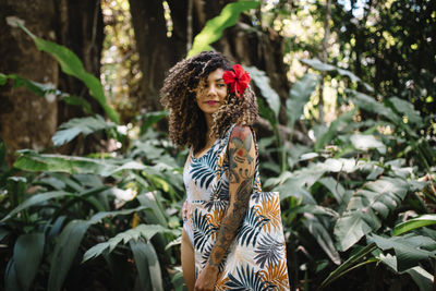 Young woman standing against plants in forest