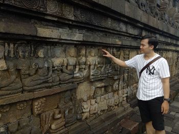 Full length of young man standing against wall