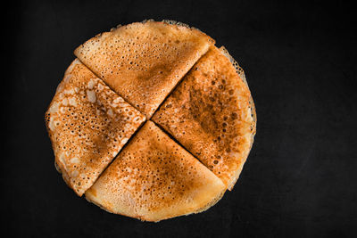 Thin pancakes on a plate on a black background. traditional russian food.