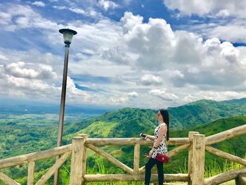 Woman standing by railing against mountain