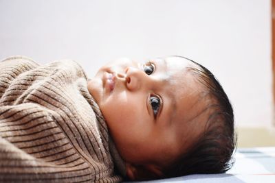 Close-up of cute baby girl lying on bed