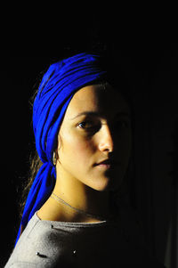 Close-up portrait of young woman against black background