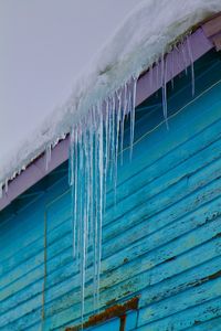 Low angle view of icicles against blue house