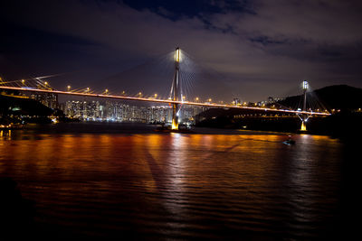 Illuminated bridge over river against sky at night