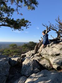 Man standing on rock against sky