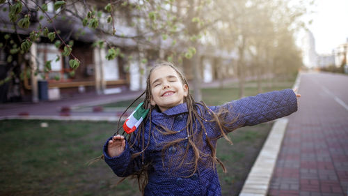 Happy girl standing against trees