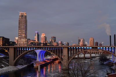 Bridge over river in city against sky