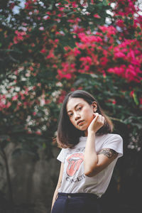 Beautiful young woman standing against pink flowering plants