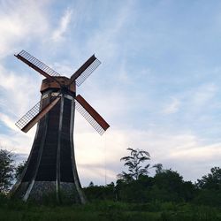 Low angle view of traditional windmill on field against sky