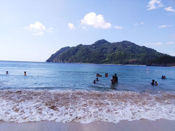 People enjoying at beach against sky