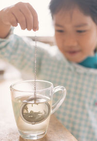 Close-up of girl playing with necklace at home