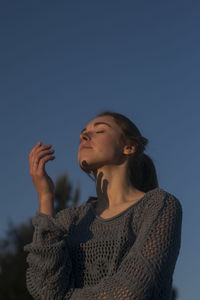 Low angle view of woman looking away against sky