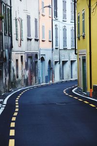 Empty road amidst buildings in city
