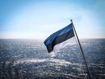 Flag in sea against blue sky