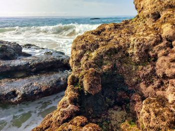 Rock formation on beach against sky