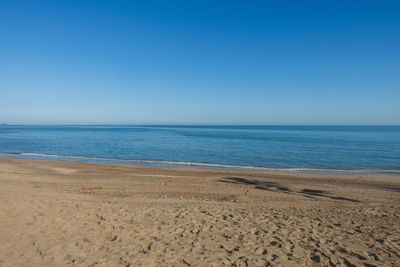 Scenic view of beach against clear blue sky