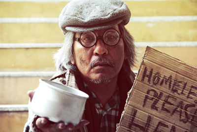 Portrait of beggar with cardboard message on steps