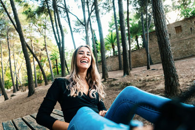 Portrait of smiling young woman sitting in forest