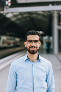 Portrait of young man standing at railroad station platform