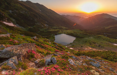 Scenic view of lake by mountains against sky during sunset