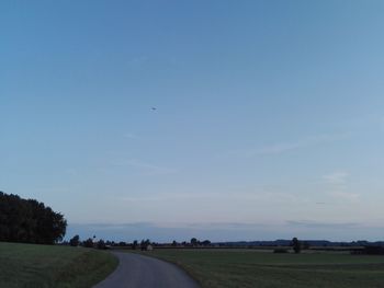 Road amidst field against sky