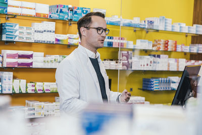 Pharmacist wearing lab coat while working in chemist shop