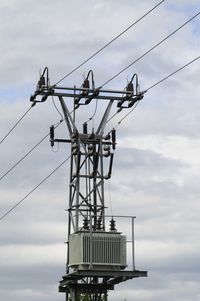 An electricity transformer with a cloudy sky in the background