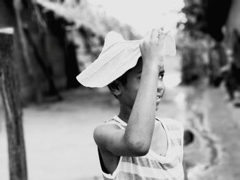 Close-up of boy holding leaf on head while standing outdoors