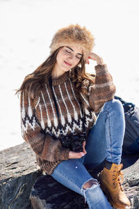 Thoughtful smiling young woman sitting on rock