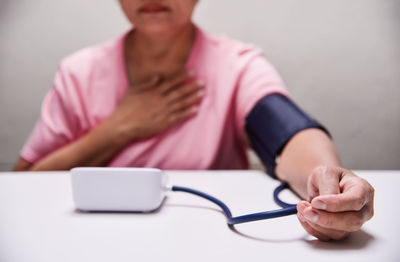 Midsection of mature woman with pressure gauge on table in hospital